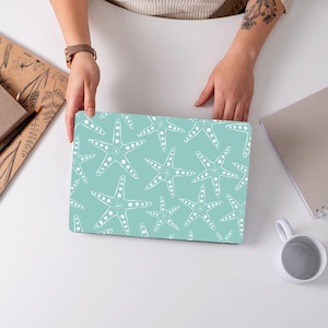May include: A teal laptop skin with a white starfish pattern. The skin is designed to fit a standard laptop.