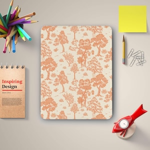 May include: A rectangular notepad with a cream-colored background and a repeating pattern of orange trees. The notepad is surrounded by pencils, a sticky note, paper clips, a pencil, and a red fish-shaped object.