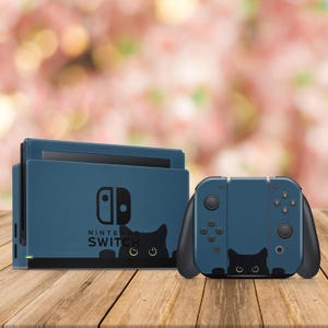 May include: A blue Nintendo Switch console and a matching blue Joy-Con controller with a black cat design. The console has the Nintendo Switch logo and the words "Nintendo Switch" printed on it.