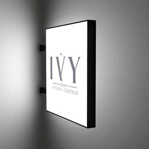 May include: A white rectangular sign with black trim and the text "IVY - Dining - Kitchen & Cocktails" on a white wall.