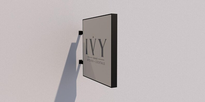 May include: Black and gray sign with the text "IVY - Dining, Kitchen & Cocktails" on a white wall.