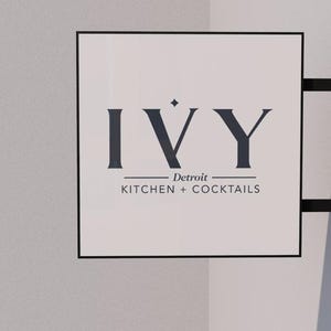May include: A white sign with black lettering that reads "IVY Detroit KITCHEN + COCKTAILS".