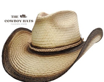 Puede incluir: Un sombrero vaquero de color marrón claro con una banda marrón oscura y un ribete de cuero trenzado. El sombrero tiene un ala ancha y una corona ligeramente puntiaguda.