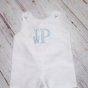 May include: White baby romper with blue embroidered initials "T.W.P."