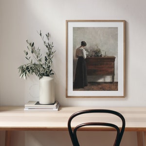 Vintage Antique Painting of a woman reading next to an antique sideboard. Printable Art hung on the wall of a modern home office decor. | Dear Alice Art