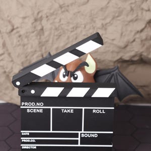 Close-up view of the 3D printed miniature director’s chair and clapperboard, highlighting the precision of the print and texture of the materials. Designed to mimic the look of real film set equipment, this collectible is perfect for creative desk decor, film student gifts, or indie filmmakers looking to add a unique touch to their studio. This photo showcases the fine details and realistic proportions that make this miniature kit a conversation starter in any setting.