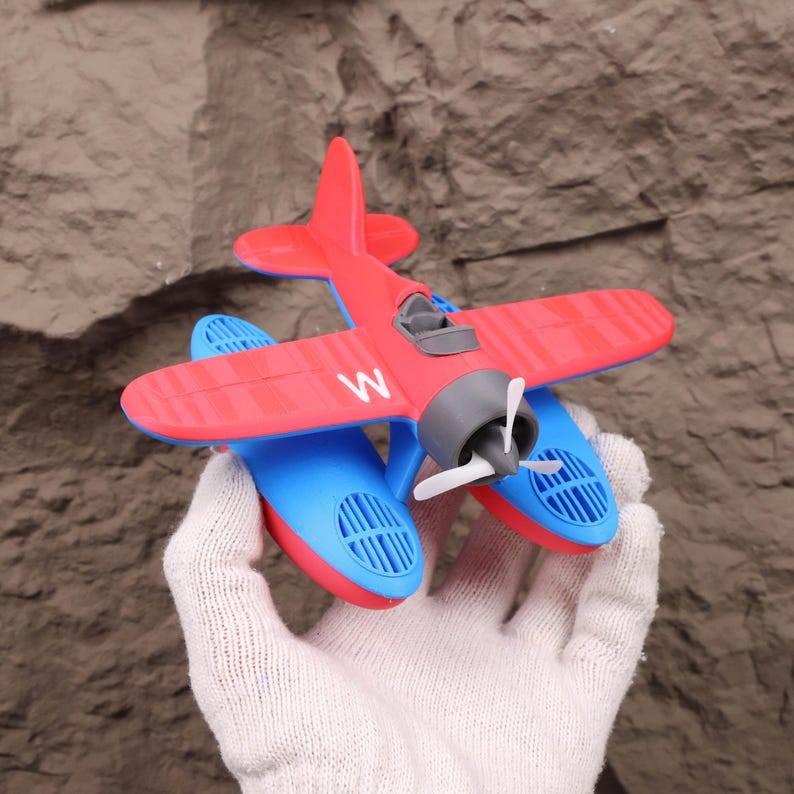 Close-up of floating seaplane model featuring detailed 3D printed design, shown on a tabletop as a unique desk or shelf decor item. Ideal for aviation enthusiasts and kids who love aircraft toys, it serves as both an educational STEM toy and a charming display piece. Great as a Christmas holiday gift, Halloween decoration, or collectible aviation-themed item. This model helps introduce kids to water science concepts while also providing hours of bathtub or pool fun.