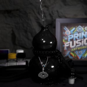 May include: A black ceramic gourd with a silver chain and a white jade pendant. Water is being poured into the gourd from above.