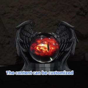 May include: A decorative orb featuring a fiery red eye design, set within a black, winged stand. The text "The content can be customized" is visible at the bottom. The orb is a striking centerpiece, ideal for gothic or fantasy decor.