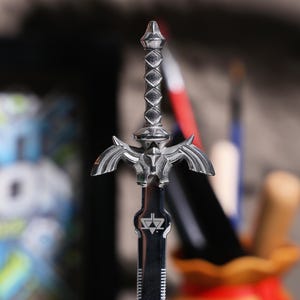 May include: A silver-colored Master Sword replica with a detailed design and a triangular symbol on the blade.