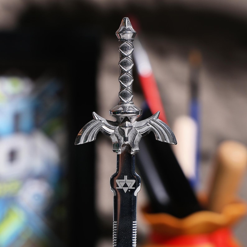 May include: A silver-colored Master Sword replica with a detailed design and a triangular symbol on the blade.