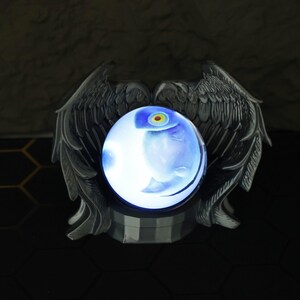 The magic orb LED display sits on a shelf surrounded by Fullmetal Alchemist and Naruto memorabilia, highlighting its customizable image projection and gamer-friendly size. With its USB-C charging feature and eerie yet stunning glow, this crystal ball is a must-have for anime collectors, fantasy fans, and those looking to give a unique holiday gift for him.