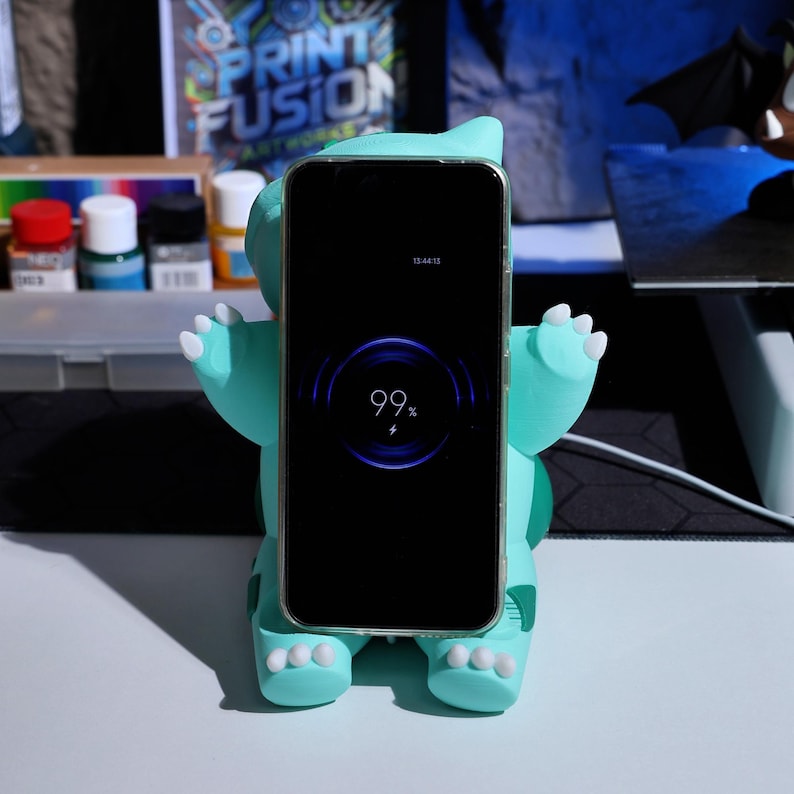 Cute and functional phone charger stand featuring a whimsical plant-inspired creature design. Ideal for gaming fans looking for a practical yet fun accessory to decorate their space and charge their devices quickly.