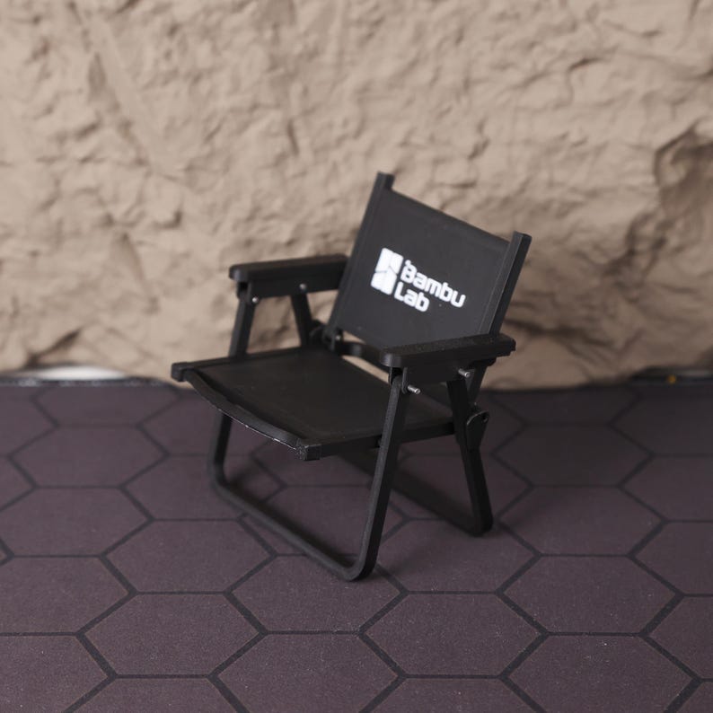 Artistic shot of the miniature film set from above, showing the layout and proportions of the chair and clapperboard together. This collectible is a tribute to the art of filmmaking and serves as a motivational symbol for creatives. Whether used as a photography prop, shelf accent, or personal keepsake, this set is an eye-catching piece for cinema fans, directors, and storytellers. The compact design ensures it fits perfectly in a variety of spaces, from home offices to studio desks.