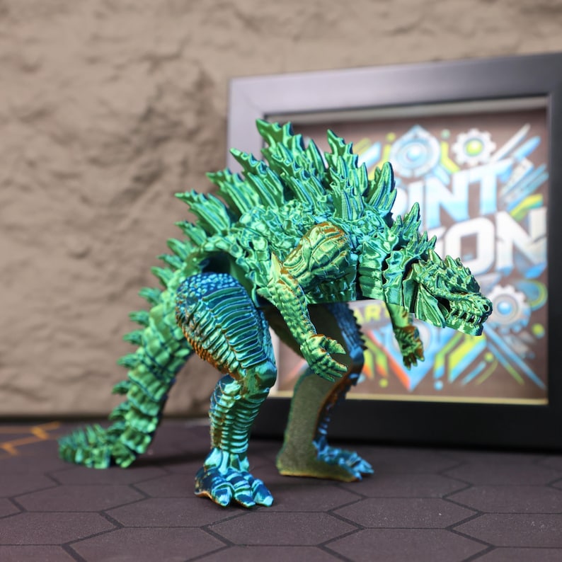 Close-up view of the electroplated Godzilla toy figure’s head and upper body, emphasizing the intricate 3D printed textures and reflective chrome surface in a striking blend of blue and green tones. The image captures the sharpness of the spines, the expression of the monster’s face, and the smooth articulation in the shoulders and arms, offering a clear look at the craftsmanship that makes it perfect for collectors, gamers, and sci-fi lovers interested in detailed, poseable figures.