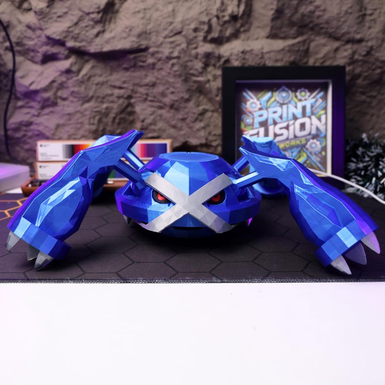 May include: A blue and white 3D printed model of a Pokemon character. The character has a large, flat head with a white X across the eyes. The character has four arms and is standing on a black surface.