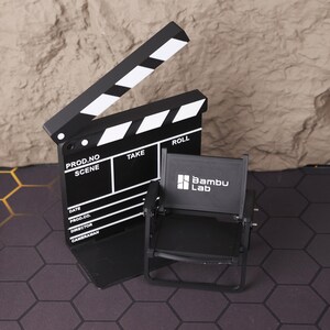 Miniature director’s film set featuring a realistic 3D printed folding chair and clapperboard, perfect for filmmakers, movie lovers, and creative professionals. This collectible set captures the charm of a Hollywood film set and adds cinematic flair to any desk or studio workspace. Ideal for photography props or as an inspiring gift for aspiring directors, screenwriters, or cinema enthusiasts.