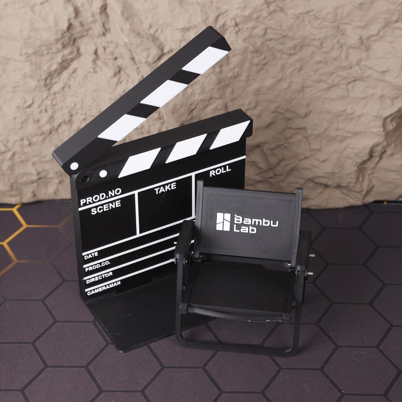 Miniature director’s film set featuring a realistic 3D printed folding chair and clapperboard, perfect for filmmakers, movie lovers, and creative professionals. This collectible set captures the charm of a Hollywood film set and adds cinematic flair to any desk or studio workspace. Ideal for photography props or as an inspiring gift for aspiring directors, screenwriters, or cinema enthusiasts.