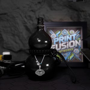 May include: A black ceramic gourd-shaped bottle with a silver chain and pendant. The bottle is decorated with a black paracord strap and a black cord.