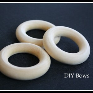 May include: Three unfinished wooden rings, perfect for crafting DIY bows. The rings are stacked on top of each other, with the largest ring at the bottom and the smallest ring at the top.