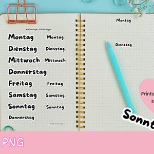 Könnte beinhalten: Ein offenes Notizbuch mit Aufklebern für die Wochentage auf Deutsch. Die Aufkleber sind schwarz und weiß. Ein rosa herzförmiger Aufkleber sagt "Printable Planner Stickers". Ein blauer Stift und ein lila Stift befinden sich auf der rechten Seite.