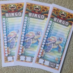 May include: Three bingo cards with a turtle and sunflower design. The word "BINGO" is at the top, with numbers 1-15 listed down the side. The bottom of the card says "CASH TABS".