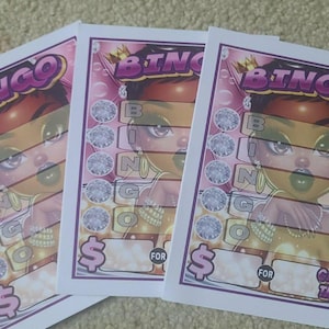 May include: Three Bingo cards with a cartoon illustration of a woman with a crown. The cards have a pink and purple color scheme with the word "BINGO" at the top. The cards also have the words "FOR" and "CASH TABS".