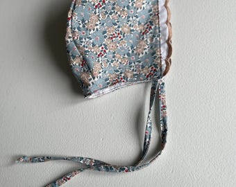 May include: A blue and white floral baby bonnet with a white lace trim and matching ties.