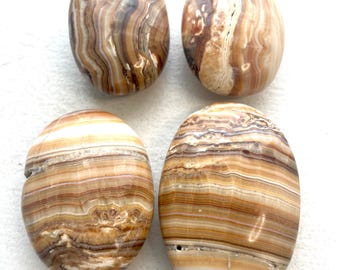 May include: Four oval-shaped polished stones with brown, white, and beige stripes. The stones are smooth and have a natural, organic look.