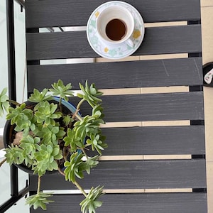 Puede incluir: Una mesa de madera gris con una taza de caf&eacute; y una planta suculenta en maceta. La mesa tiene un dise&ntilde;o de listones y est&aacute; hecha de madera.