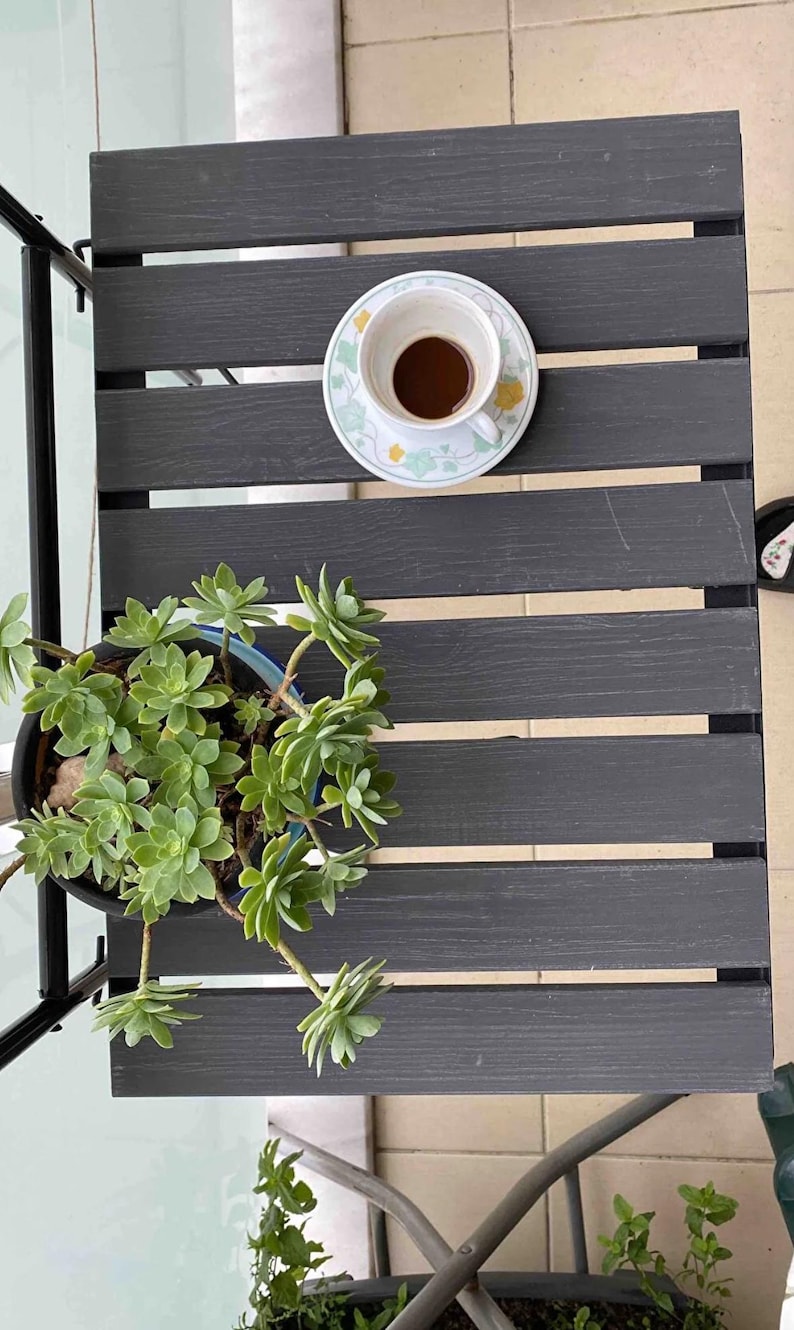 Puede incluir: Una mesa de madera gris con una taza de caf&eacute; y una planta suculenta en maceta. La mesa tiene un dise&ntilde;o de listones y est&aacute; hecha de madera.