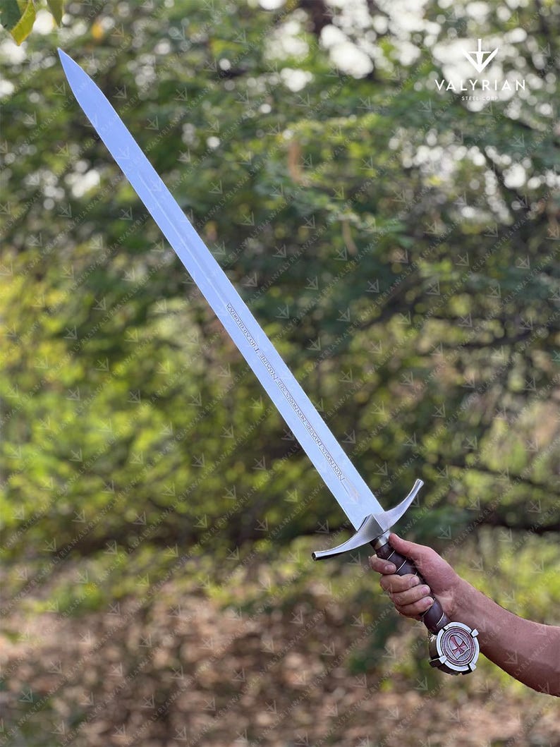 The Accolade Sword of the Knights Templar is a magnificent weapon of ceremony and devotion — a blade worthy of a Grand Master himself. Named “The Accolade,” this sword symbolizes the moment of knighthood, where a loyal member of the Order would be dubbed in service of faith. Its Latin inscription, “Non Nobis, Domine, Non Nobis, Sed Nomini Tuo Da Gloriam” defines the creed and humility of the Templars who shaped medieval history through faith and steel.