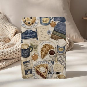 May include: A rectangular decorative sign featuring a collage of Stars Hollow themed illustrations including a blueberry muffin, a Luke's mug, a stack of books, a croissant, a Doose's Market coffee bag, a slice of cherry pie, and handwritten text notes.