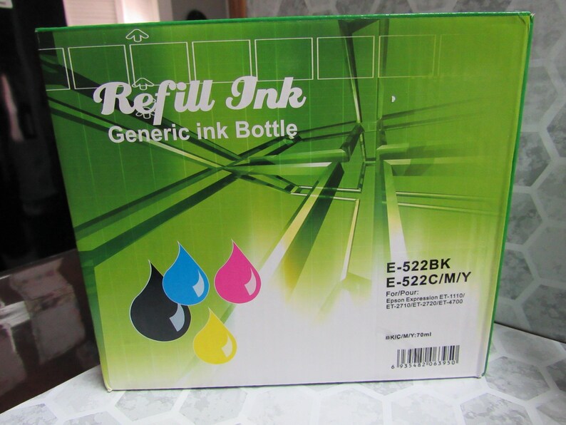 Op de afbeelding: Een groene doos met het opschrift "Refill Ink" en de tekst "Generic ink Bottle". De doos bevat kleurrijke inkt druppelafbeeldingen in zwart, blauw, roze en geel. De doos vermeldt ook de modelnummers E-522BK en E-522C/M/Y.
