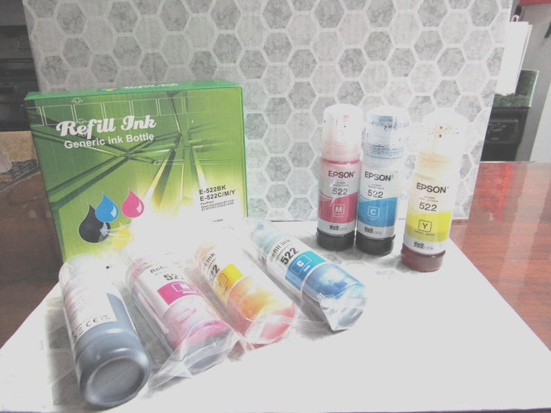 Op de afbeelding: Een groene doos met het opschrift "Refill Ink" en een generieke inktfles, samen met verschillende inktflessen in verschillende kleuren. De flessen zijn voorzien van het opschrift "Epson 522" en bevatten zwarte, magenta, cyaan en gele inkt.