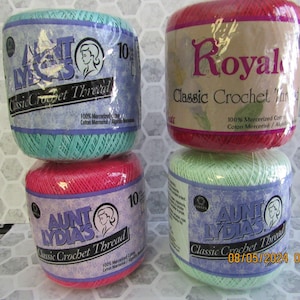 May include: Four spools of crochet thread in various colors. Two spools are labeled "Aunt Lydia's Classic Crochet Thread" and two are labeled "Royal Classic Crochet Thread". The colors include teal, pink, red, and light green. Each spool is wrapped in clear plastic.