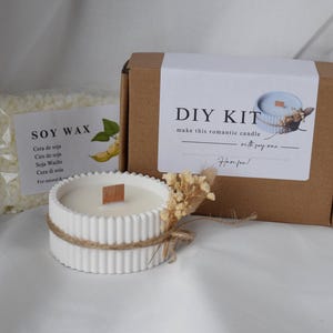 K&ouml;nnte beinhalten: Ein DIY-Kerzen-Set mit Sojawachs, einem wei&szlig;en Beton-Kerzenhalter und einer Box mit dem Text "DIY KIT make this romantic candle with soy wax".