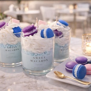 Puede incluir: Tres velas de cristal con un diseño azul y blanco, cubiertas con crema batida y macarons. Un plato con macarons y arándanos está cerca. Las velas tienen el texto "Sweet Macaron".