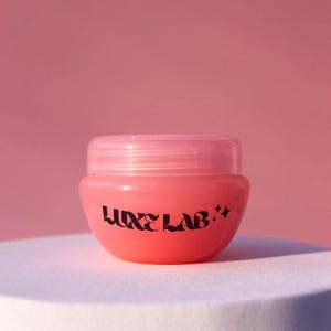 May include: A pink jar with a clear lid and a black label that says "LUXE LAB."