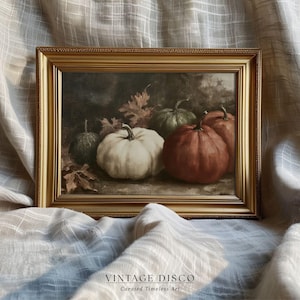 Puede incluir: Pintura enmarcada de naturaleza muerta con calabazas en tonos blanco, verde y rojo-naranja, con hojas de otoño. La obra de arte está ambientada sobre un fondo oscuro y enmarcada en un marco dorado. El texto "VINTAGE DISCO Curated Timeless Art" está en la parte inferior.