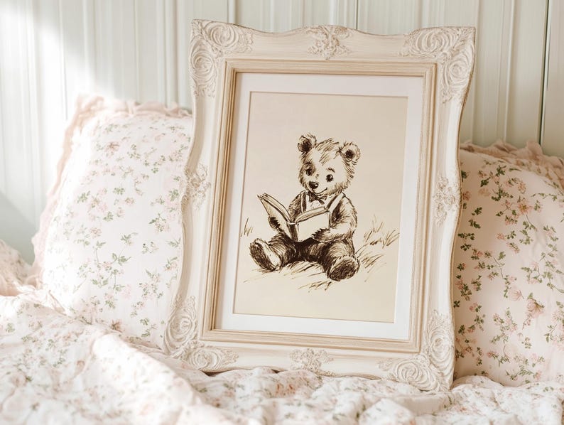 May include: A framed sepia-toned print of a teddy bear reading a book. The ornate, cream-colored frame is set against a backdrop of floral pillows and bedding. The image evokes a sense of nostalgia and comfort, suitable for a nursery or bedroom.