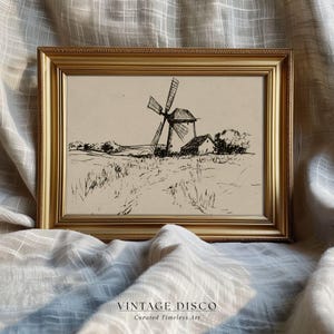 May include: A framed black and white sketch of a windmill and small building in a field. The artwork is in a gold frame and set against a neutral fabric background. The text "VINTAGE DISCO Curated Timeless Art" is at the bottom.
