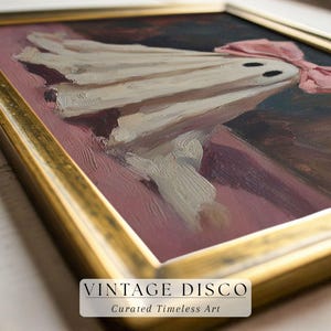 May include: An oil painting in a gold frame depicts a whimsical ghost with a pink bow. The ghost is draped in white fabric with two black eyes. The background is a mix of dark and light colors, with the text "VINTAGE DISCO" at the bottom.