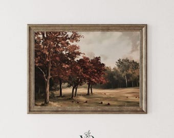 Puede incluir: Un cuadro de paisaje en un marco de bronce texturizado que representa un campo con árboles de otoño de color rojo oscuro bajo un cielo nublado. La escena presenta objetos oscuros dispersos en el suelo y un pequeño logotipo floral en el centro.