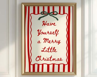 May include: A framed Christmas print with a gold frame. The artwork features a cream background with red vertical stripes and a central cream rectangle with the words "Have Yourself a Merry Little Christmas" in red script. A green bow is at the top.