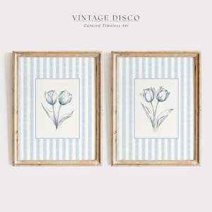 Puede incluir: Dos obras de arte enmarcadas. Cada una presenta un fondo a rayas azules y blancas con un borde blanco. Dentro del borde hay una ilustración botánica de tulipanes azules. Los marcos son de color marrón claro. El texto "VINTAGE DISCO" y "Curated Timeless Art" está en la parte superior.