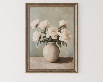May include: A framed oil painting depicting a bouquet of pale pink and white peonies arranged in a rounded beige ceramic vase. The artwork features a muted sage green background and a neutral-toned surface, all enclosed within a metallic frame.