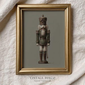 Puede incluir: Impresión enmarcada de un soldado cascanueces de estilo vintage en un marco dorado. El cascanueces viste un uniforme verde y blanco, un sombrero detallado y una barba blanca. El texto "VINTAGE DISCO" aparece en la parte inferior.