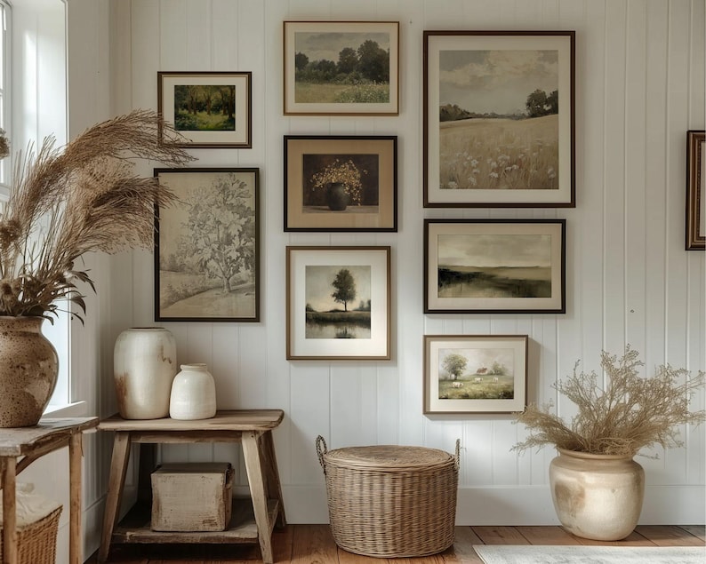May include: A gallery wall featuring framed landscape art in various sizes and styles. The artwork includes depictions of fields, trees, and serene natural scenes. Decorative vases and a woven basket add to the room's rustic aesthetic.