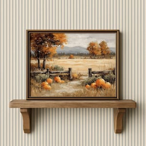 May include: Framed landscape painting depicting an autumn scene with pumpkins, a wooden fence, and trees with orange foliage. The artwork is displayed on a wooden shelf against a striped wallpaper background.